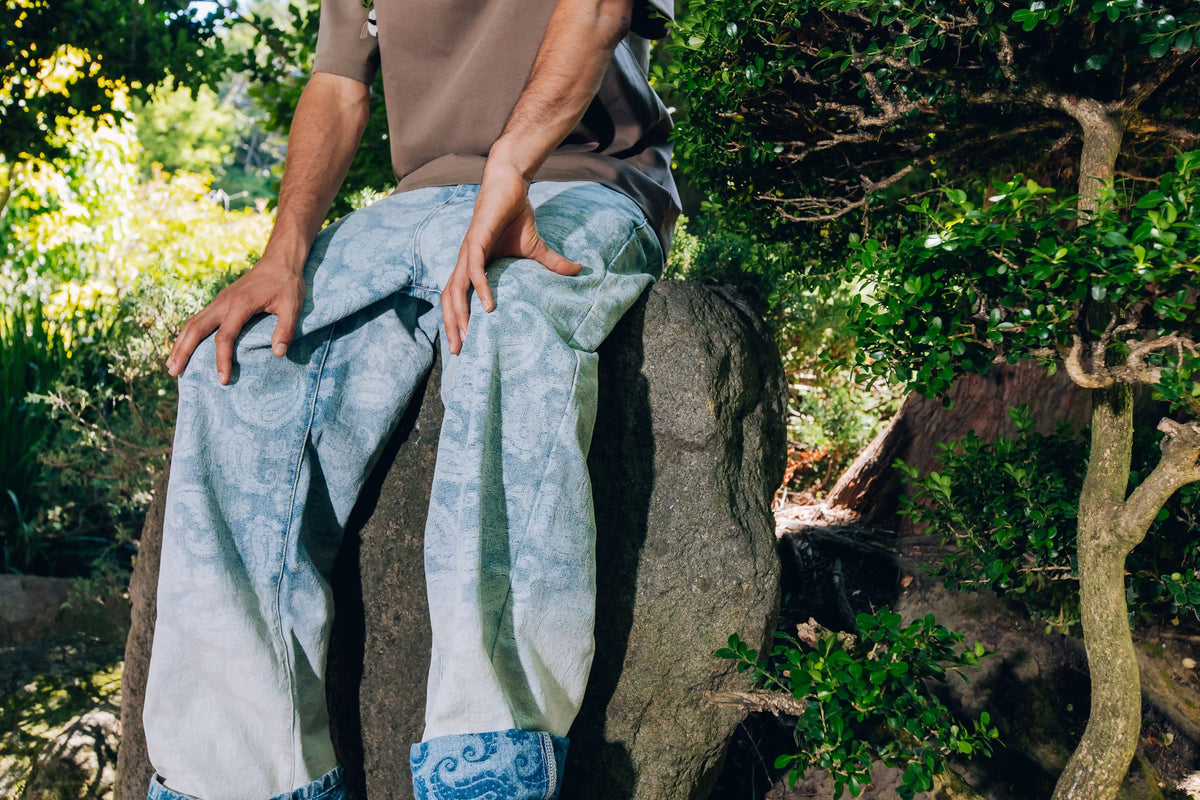 Axis Studios Denim Jeans - Model wearing Porcelain Wash Jacquard wide-leg jeans with cuffed hem in Japanese garden setting