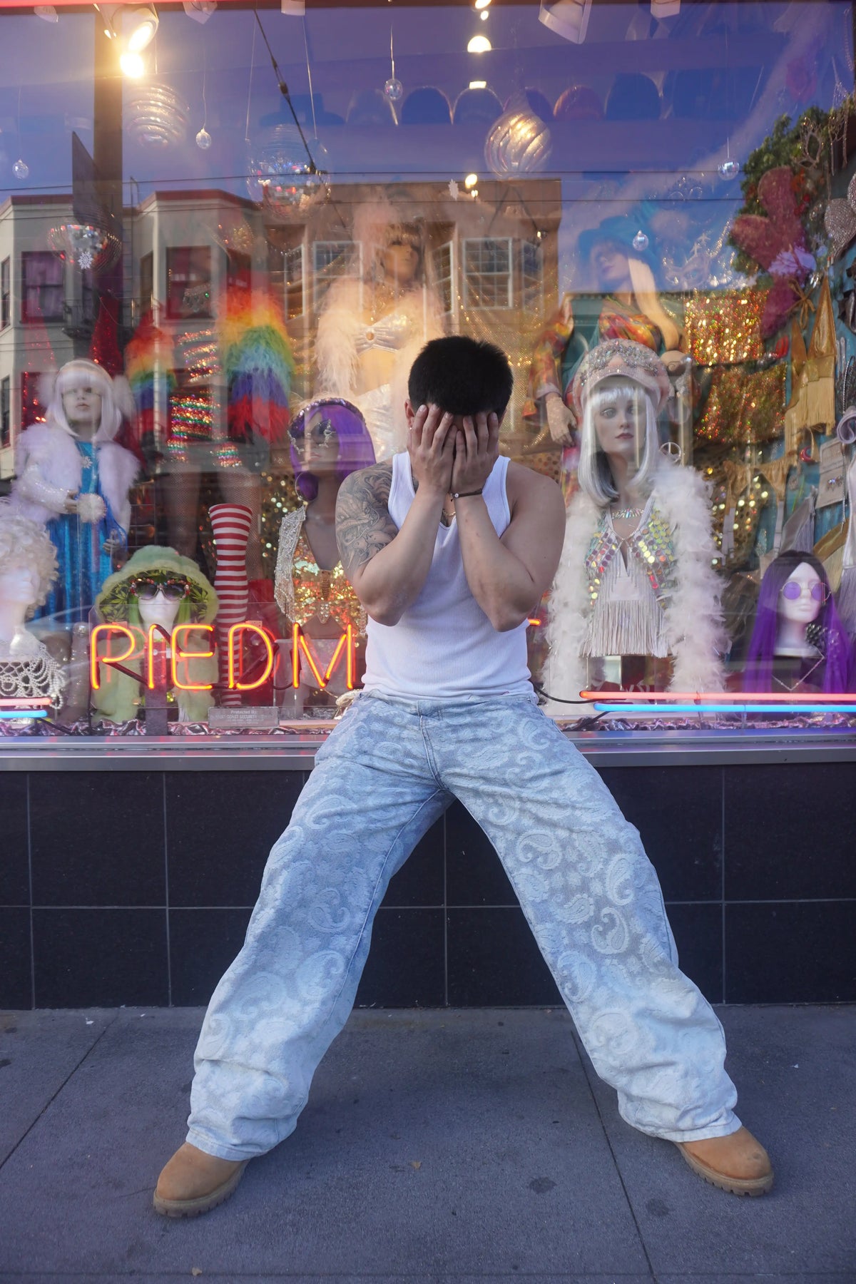 Axis Studios Denim Jeans - Model wearing Porcelain Paisley Jacquard wide-leg jeans with white tank top in front of colorful storefront