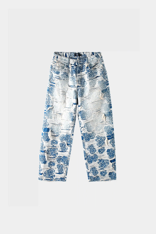 Light blue denim jeans with blue-white porcelain rose jacquard pattern and heavy distressing, wide-leg fit, front view on white background.
